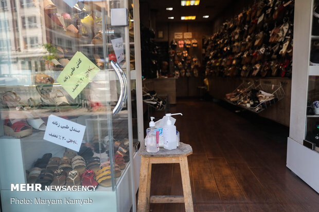 قرار دادن ژل و محلول ضدعفونی توسط صاحب مغازهای در خیابان انقلاب تهران جهت رعایت بهداشت مشتریانش